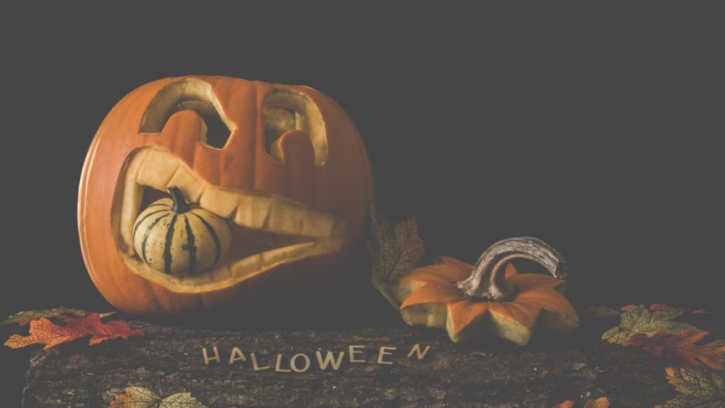 Carved jack-o'-lantern with a gourd and autumn leaves. Perfect for Halloween decor.