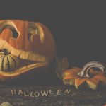 Carved jack-o'-lantern with a gourd and autumn leaves. Perfect for Halloween decor.