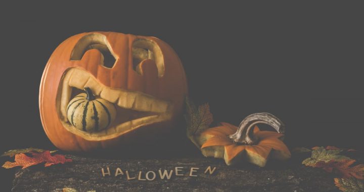 Carved jack-o'-lantern with a gourd and autumn leaves. Perfect for Halloween decor.